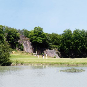 Golfbane med vand i forgrunden og store klipper i baggrunden