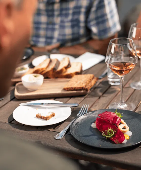 Bord med fyldte vinglas, brød og tallerkner med mad