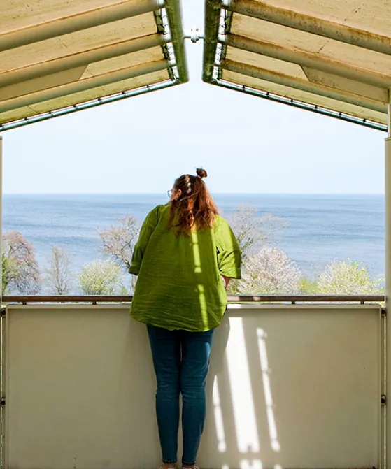 Kvinde kigger ud over vandet fra udkigspost ved Bornholms Kunstmuseum