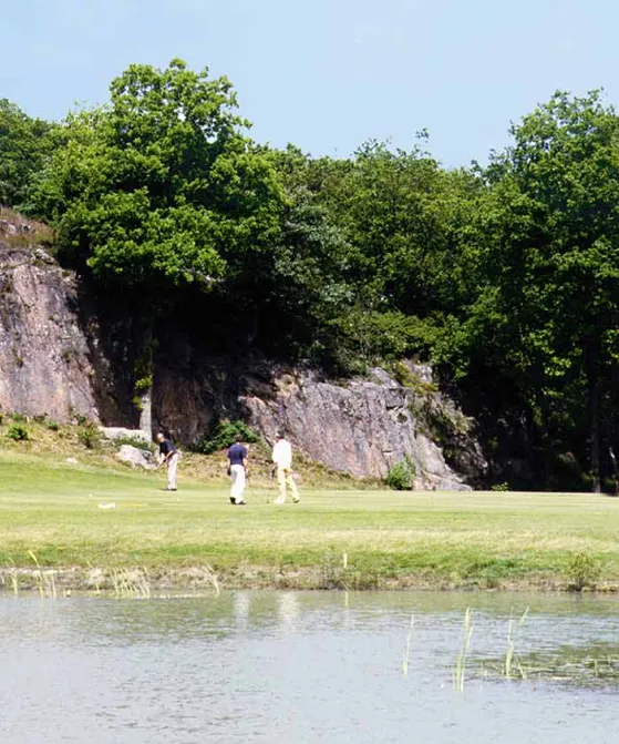 Tre personer spiller golf ved klipper