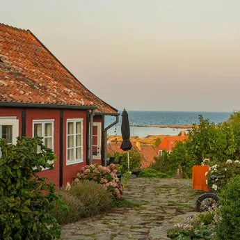 Rødt bindingsværk med mange grønne planter i Svaneke på Bornholm