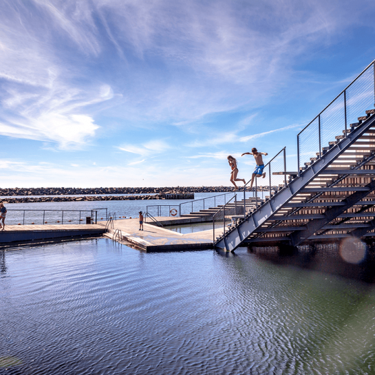 Personer hopper i vandet fra badeplatform ved Hasle Havn