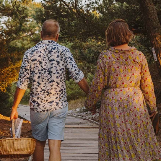 Par går hånd i hånd på sti med picnickurv