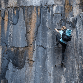 Kvinde klatrer på klippe