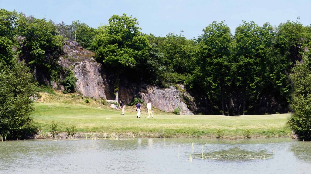 Tre personer spiller golf ved klipper